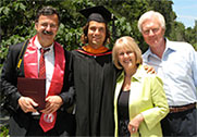 Two male internationals in graduate robes with their member host couple.