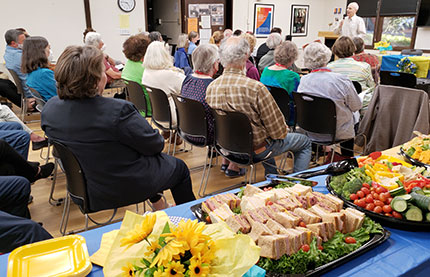 CCIS membership audience listening to speaker. Table of event food is in the foreground.