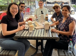 Photo of internationals chatting and enjoying lunch on campus with their host family
